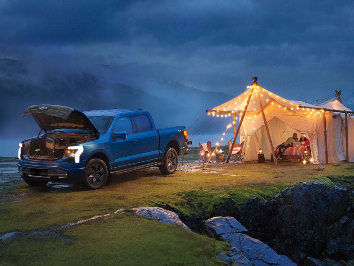 A F-150 Lightning® outside powering the lights at a campsite.