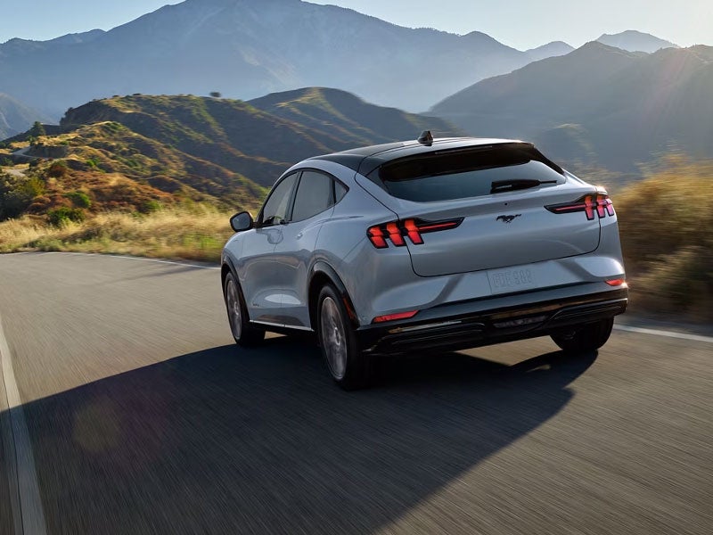 Ford vehicle driving on a paved road with a scenic mountain view