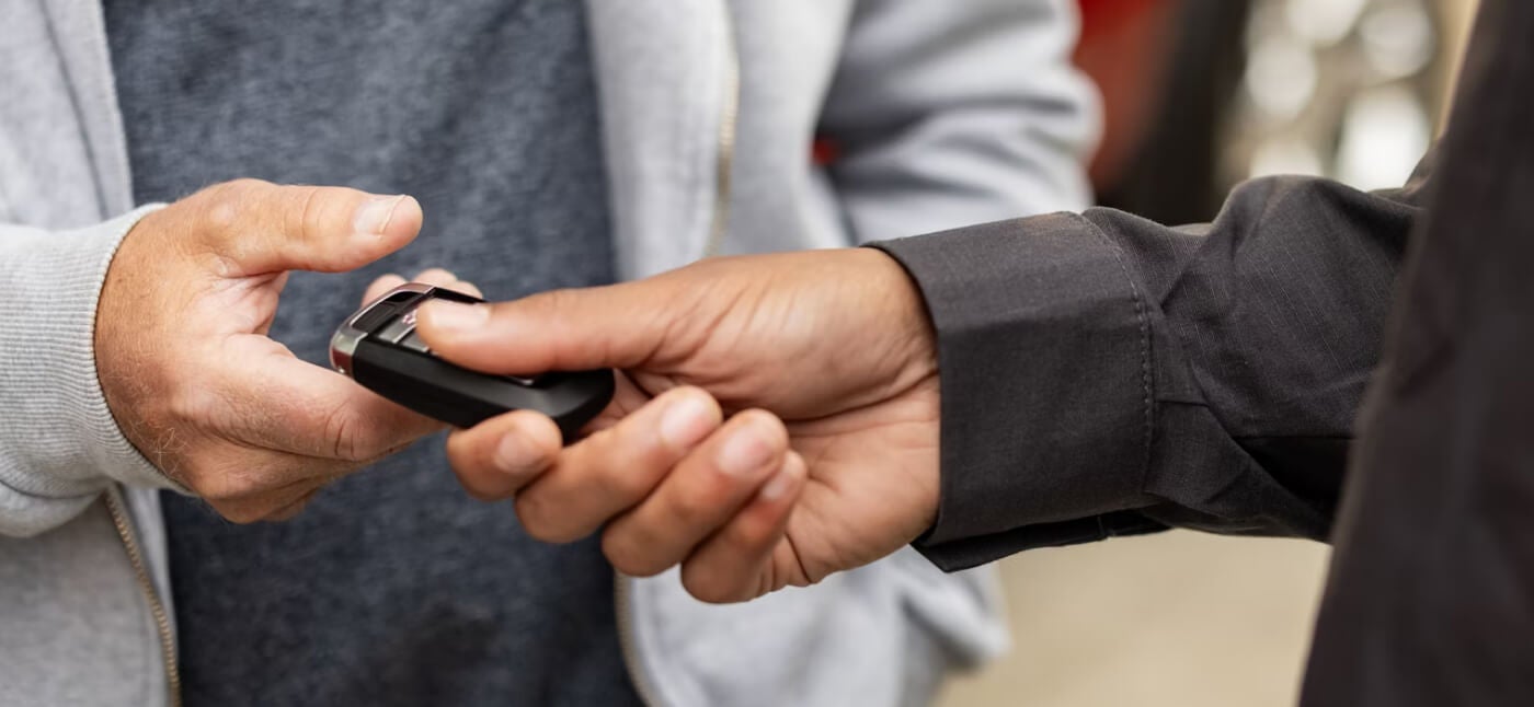 A close-up of hands exchanging a Ford key.