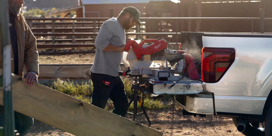 Man using power saw on the back of Ford Pickup Truck